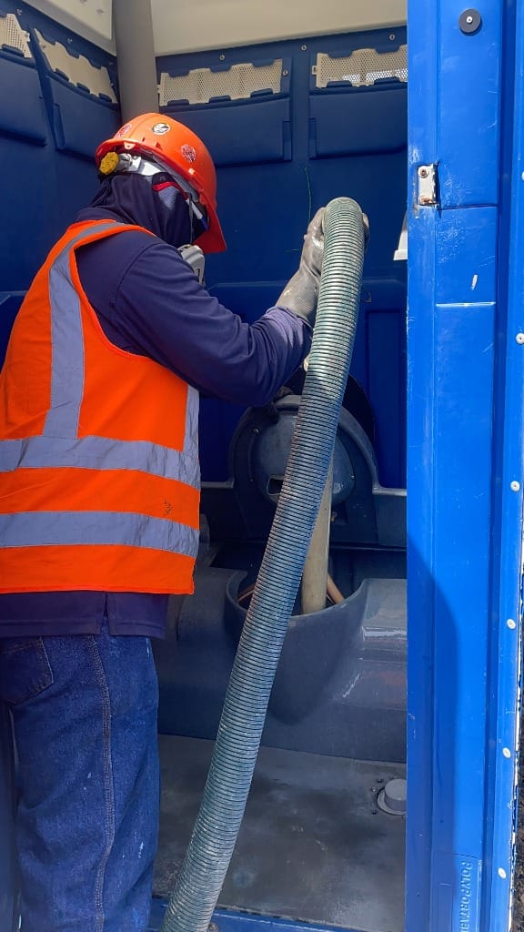 Técnico de SEPPSA realizando succión y limpieza en un baño portátil